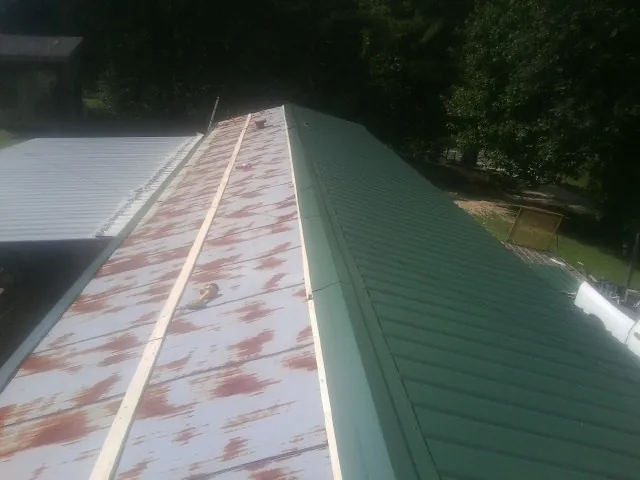 Old rusted panels beside newly installed green metal roofing — Wind Damage Roof Repair by Roofing Brothers in Elizabethtown