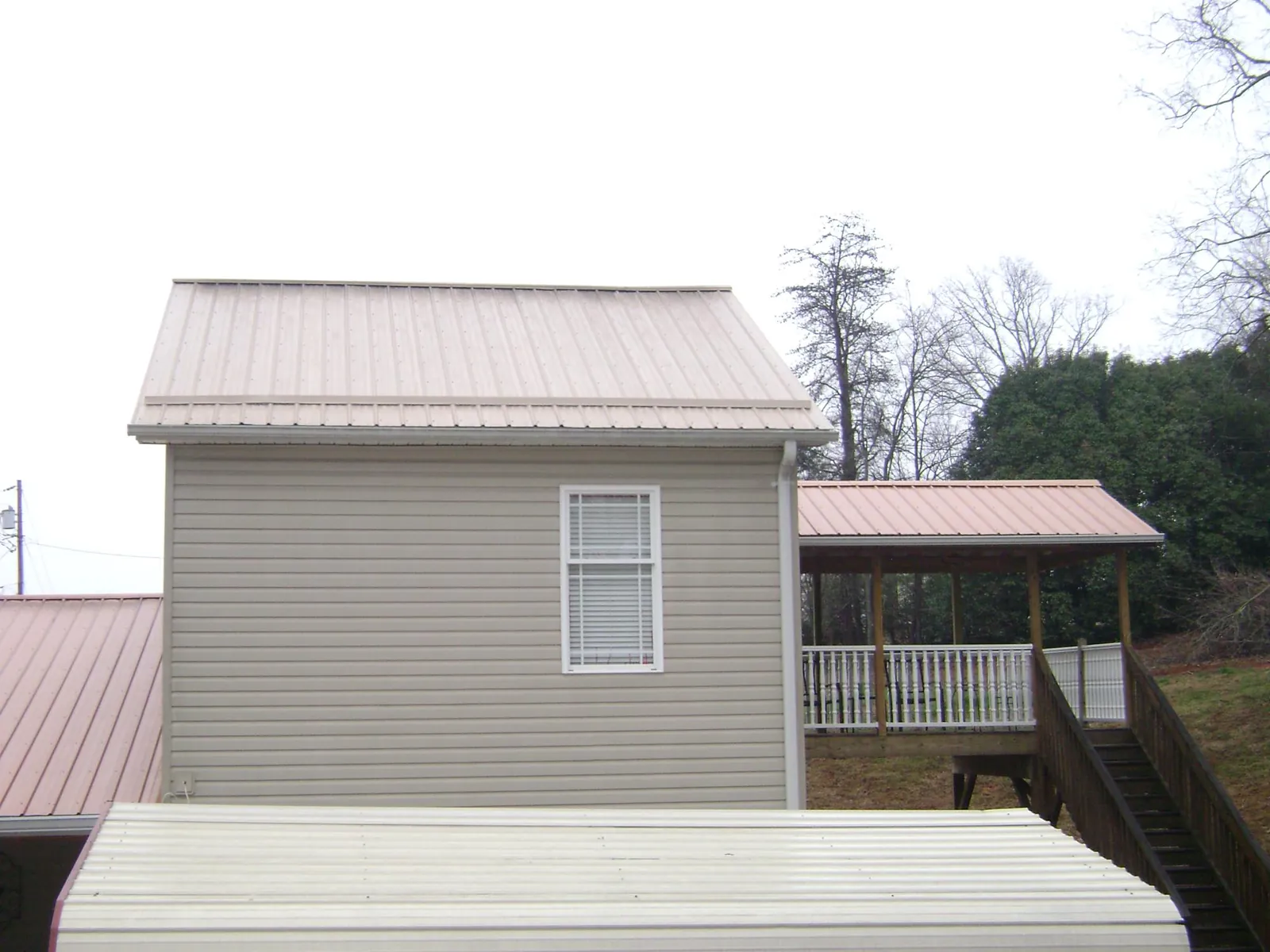 Tan metal roofs on a two story addition and attached porch, from a Roof Replacement job in Elizabethtown
